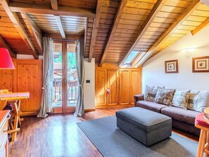 Ein Holzinnenraum mit einer Couch, einem Hocker und einem Tisch mit einer roten Lampe.