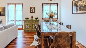Een eetruimte met een houten tafel, stoelen, een kroonluchter en een decoradiekast.