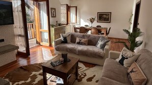 Een woonkamer met een bank, salontafel en een eethoek met stoelen en een tafel.
