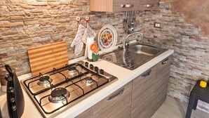 A compact kitchen with a gas stove, a sink, and wooden cabinets. - Wonderful private villa for 6 guests with A/C, WIFI, private pool, TV and patio (Syracuse)