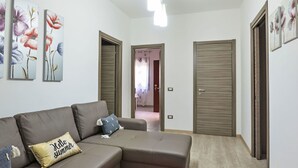 A modern living room with a sectional sofa, a red rug, and floral artwork on the walls. - Wonderful private villa for 6 guests with A/C, WIFI, private pool, TV and patio (Syracuse)