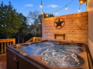 A hot tub with a wooden deck, a star decoration, and string lights. - Canyon Cottage: Hill Country Getaway, Hot Tub & Fire Pit, Mins to Whitewater Amphitheater & Tubing (Canyon Lake)