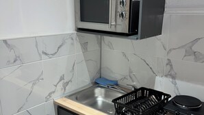 A compact kitchen with a built-in microwave, a sink, and a small countertop. - Le Darcy / DIJON train station and city center (Dijon)