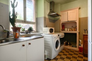 Une cuisine compacte équipée d’un lave-linge, d’un four à micro-ondes et d’un évier.