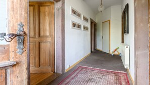 Un couloir avec une porte en bois, un radiateur, un tableau accroché au mur et un jouet d’enfant.