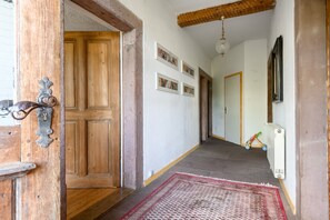 Un couloir avec une porte en bois, un radiateur, un tableau accroché au mur et un jouet d’enfant.
