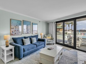 Un salon avec un canapé bleu, une table basse blanche et un fauteuil avec un coussin.