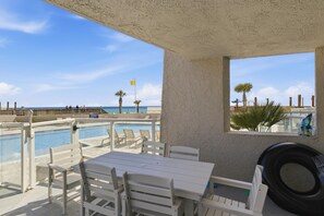 A poolside area with a table and chairs, a view of the ocean, and a flag. - Inviting 2 Bedroom Condo in Beachside II at Sandestin Golf and Beach Resort (Miramar Beach)