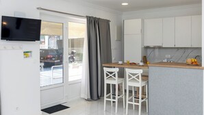 A modern kitchen with white cabinets, a wooden island, and a flat-screen TV mounted above the island. - Sunny Palace Studio 3 (Dubrovnik)