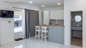 A modern kitchen with white cabinets, a grey countertop, and two white bar stools. - Sunny Palace Studio 3 (Dubrovnik)