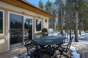 Une terrasse avec une table et des chaises, une porte-fenêtre coulissante et un barbecue.