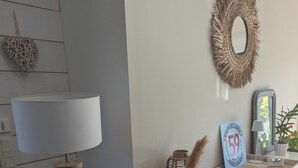 Un saló modern amb una làmpada blanca sobre un trípode, un mirall decoratiu i un ram de plomes de panícies.