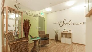 A spa room with wicker furniture, a glass cabinet, and a wall sign reading "LASS DIE Seele BAUME". - Kaiserhof Feldberg by Belvilla Resorts-twin Room (Feldberger Seenlandschaft)
