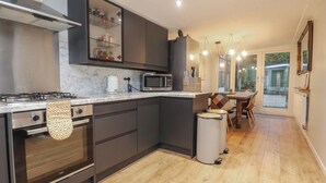 Eine moderne Küche mit integriertem Kochfeld, Mikrowelle und Backofen. Durch eine Glastür ist ein Essbereich mit Tisch und Stühlen zu sehen.