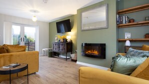 Ein Wohnzimmer mit Kamin, Sofas, Fernseher und Bücherregal.