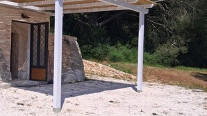 Ein überdachter Außenbereich mit einer Steinmauer, einer Holztür und einer weißen Pergola-Konstruktion.