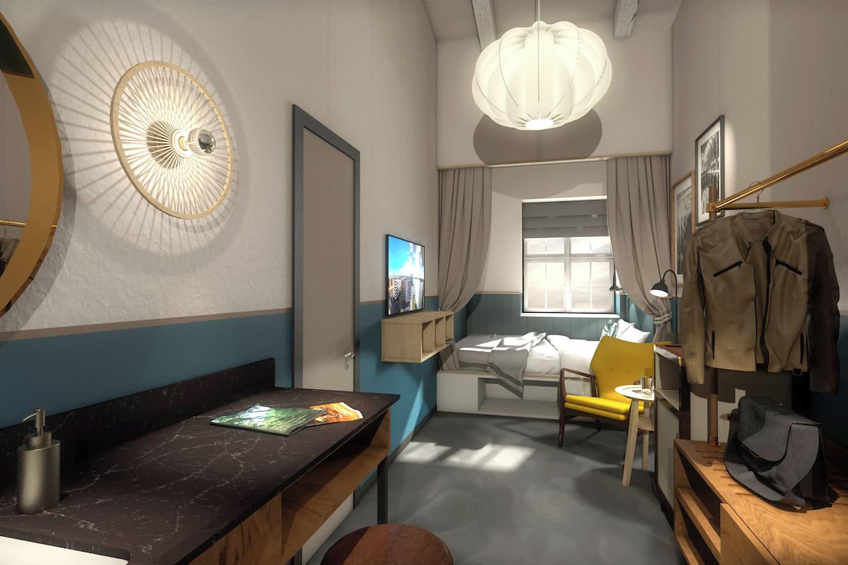 Hotellihuone, jossa on sänky, työpöytä, tuoli, vaatekaappi, peili, ikkuna ja kattovalaisin.