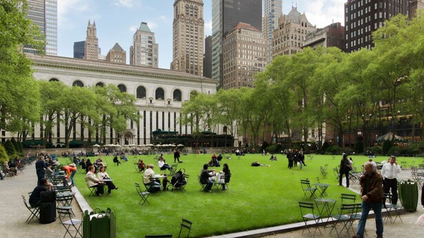 A park with green grass and trees, surrounded by buildings. - Steps to Madison Square Garden + Free Breakfast (New York City)