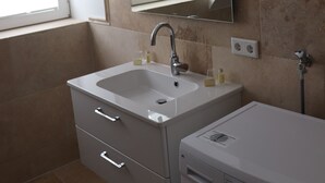 A bathroom with a sink, mirror, and a washing machine. - Welcome to the Boskop vacation apartment (Stade)