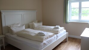 A bedroom with two beds, a nightstand, and a window with curtains. - Welcome to the Boskop vacation apartment (Stade)