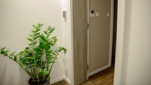 A hallway with a potted plant, a wooden door, and a light switch on the wall. - Krško garni (Krsko)