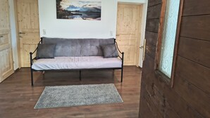 Una habitación con sofá, alfombra, puertas de madera y un cuadro en la pared.