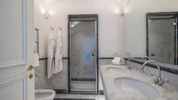 Un baño con ducha, dos lavamanos, inodoro y un espejo grande.