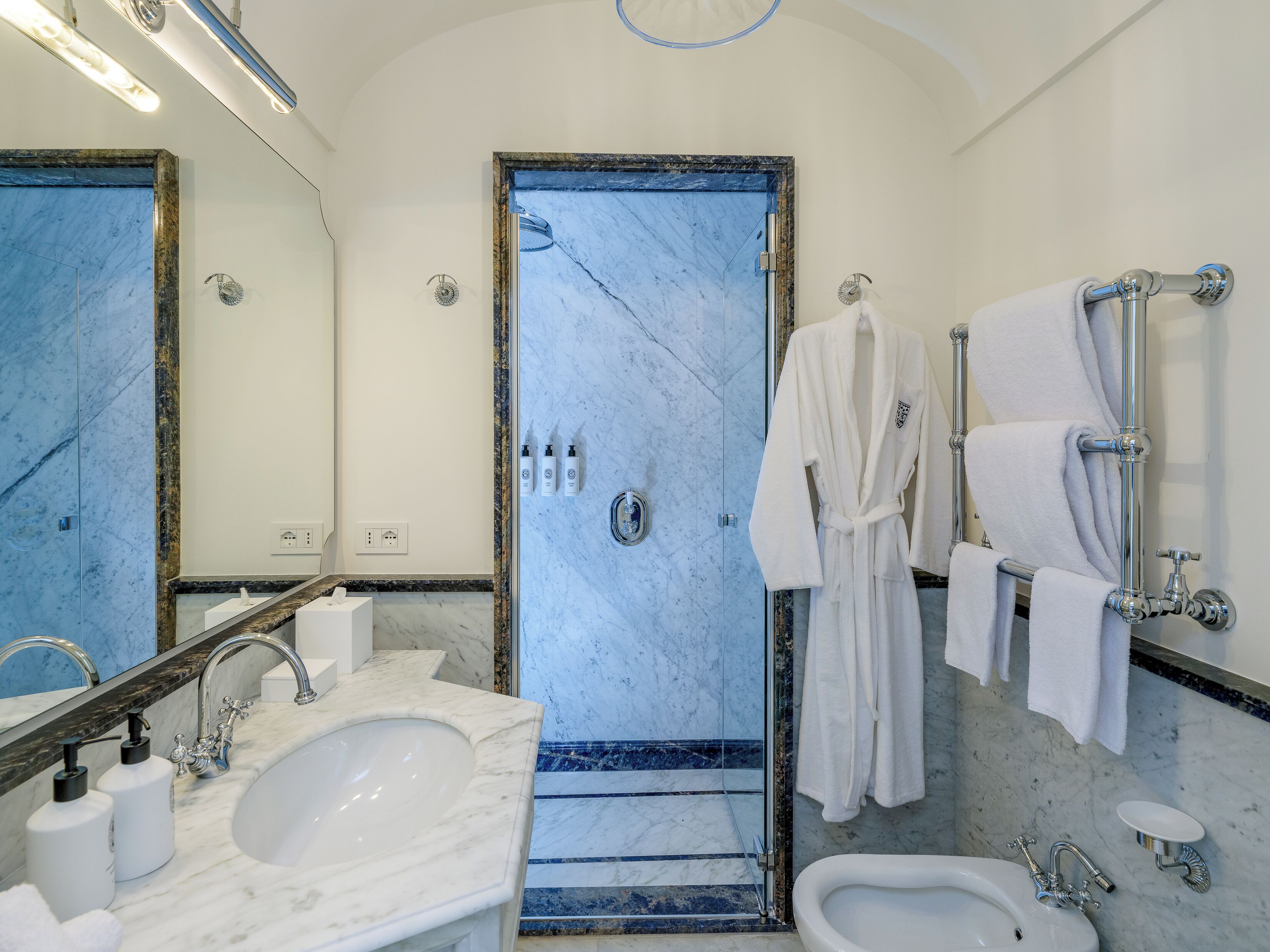 Een badkamer met een marmeren wastafel, een bidet, een bad en een douche.