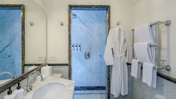 Een badkamer met een marmeren wastafel, een bidet, een bad en een douche.