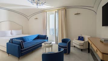 Ein Hotelzimmer mit einem Bett, einem blauen Sofa, einem weißen Sessel, einem kleinen Tisch und einem Schreibtisch.