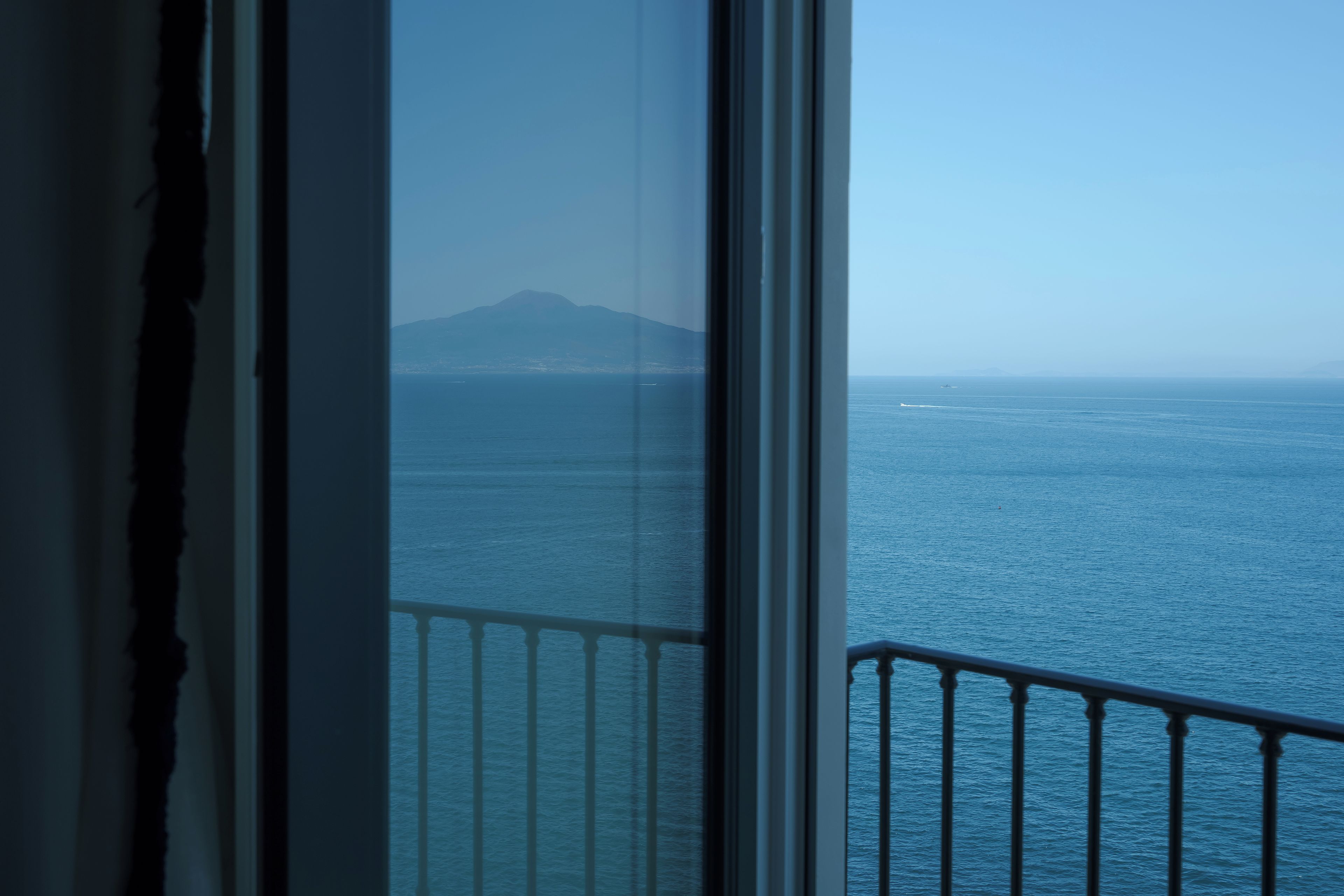 Blick vom Balkon auf ein ruhiges Meer mit einer entfernten Bergkette.
