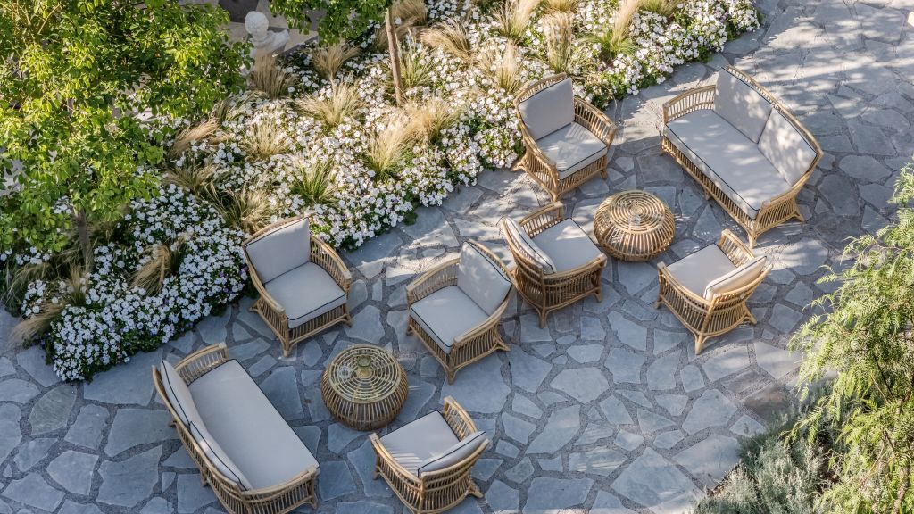 An outdoor seating area with wicker furniture and a stone floor.