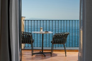 A balcony with a table and chairs, overlooking a body of water. - Hotel du Tasso (Sorrento)