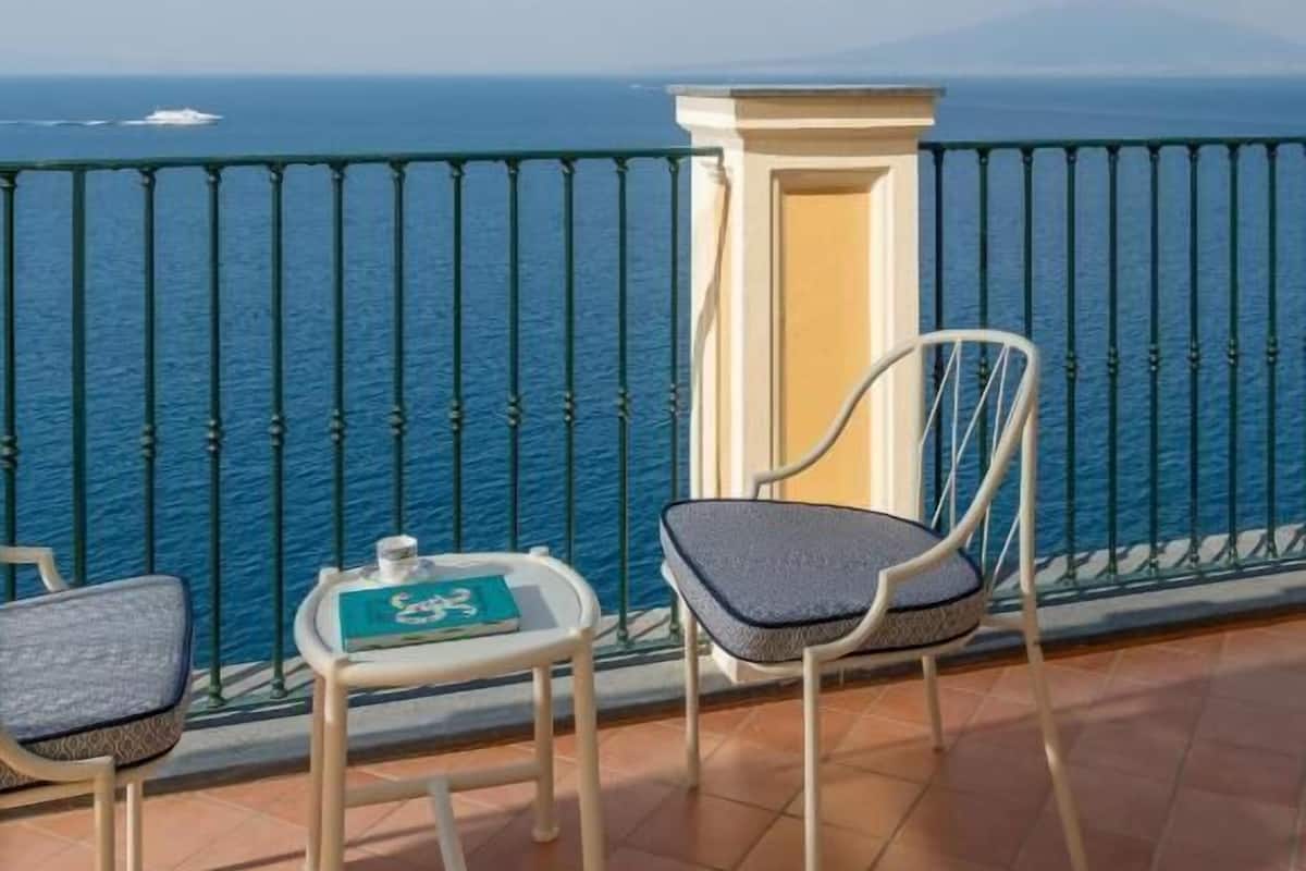 Un balcón con dos sillas y una mesa pequeña, con vista al mar.