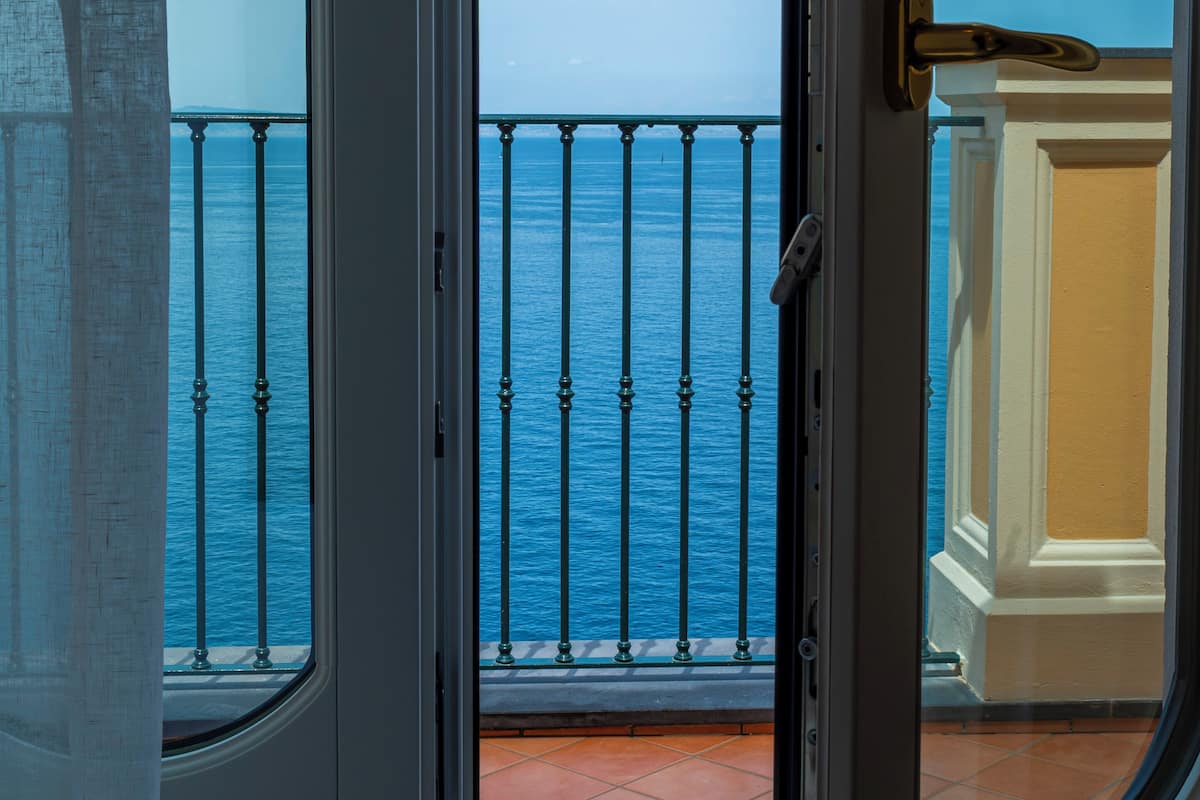 Un balcón con vista al mar y barandilla de metal.