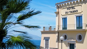 A building with a sign reading 'HOTEL DU TASSO,' a balcony with a railing, and a street lamp. - Hotel du Tasso (Sorrento)