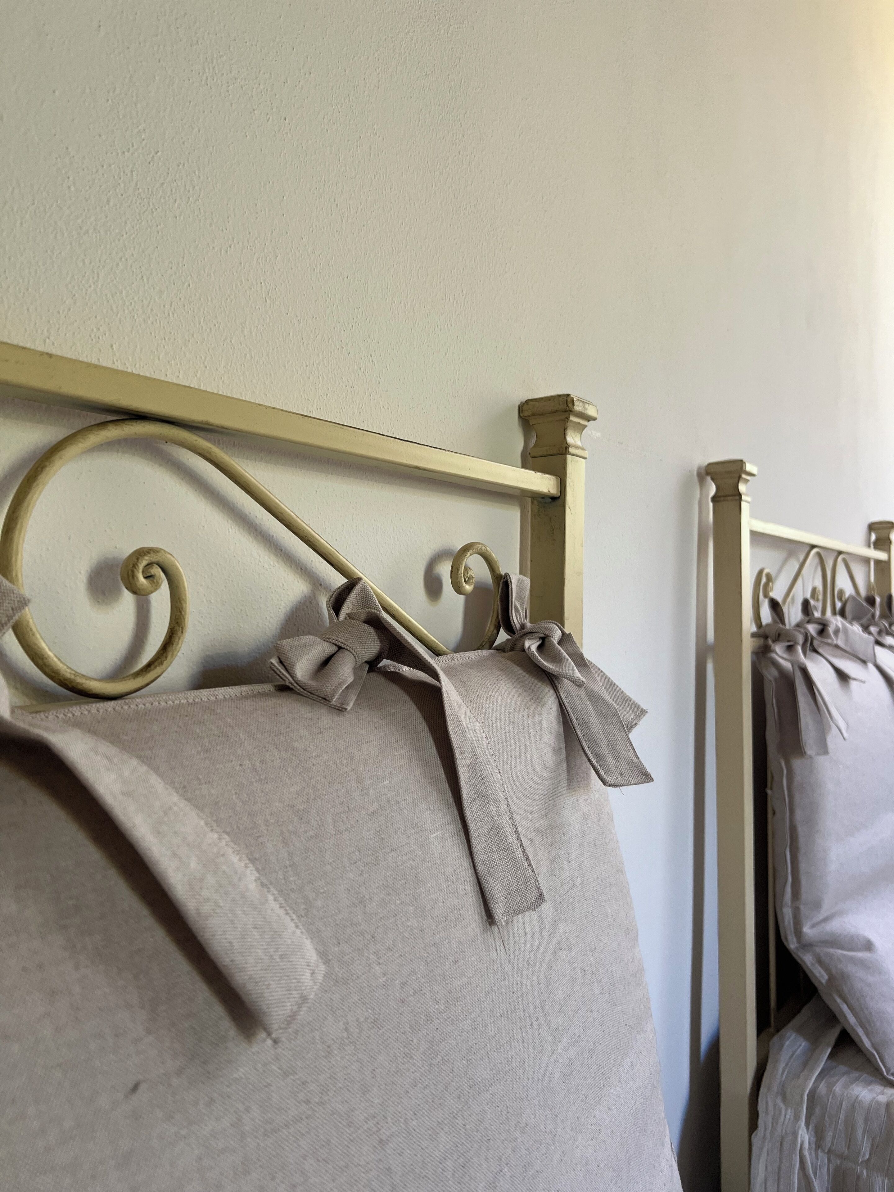 A bed with a metal headboard and decorative bows on the pillows.