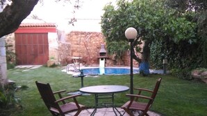 A patio with a round table and two chairs, a bird feeder, and a small pool. - Tictágora House: House 3 (Plasenzuela)