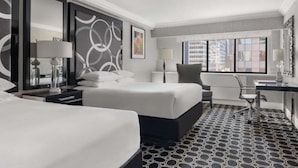 A hotel room with two beds, a desk, and a chair.