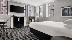 Une chambre d’hôtel avec un lit, un bureau, une chaise, une télévision et une fenêtre.