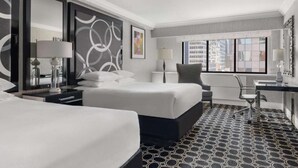 Une chambre d’hôtel avec deux lits, un bureau et une chaise.