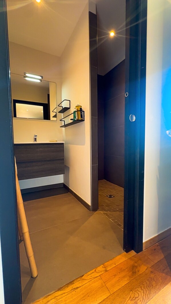 Ein modernes Badezimmer mit Spiegel, Waschbecken und Regalen.