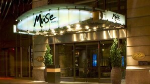 Un hotel con un cartel luminoso que dice "MUSE HOTEL" y el número "130" en la fachada.