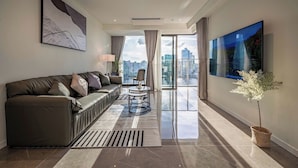 A modern living room with a sofa, a coffee table, and a view of the city through large windows. - OPERA Premier Residence By An Gia Hospitality (Ho Chi Minh City)