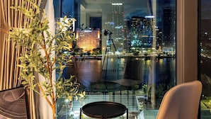 A modern room with a view of a cityscape at night, a small table, a chair, and a potted plant. - OPERA Premier Residence By An Gia Hospitality (Ho Chi Minh City)