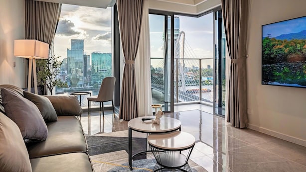 A modern hotel room with a large window offering a city view, a sofa, a small table, and a chair. - OPERA Premier Residence By An Gia Hospitality (Ho Chi Minh City)