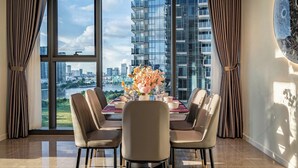 A dining area with a table set for four, large windows, and a city view. - OPERA Premier Residence By An Gia Hospitality (Ho Chi Minh City)