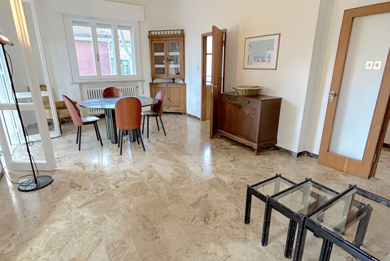 Un coin repas avec une table ronde, des chaises, un buffet et une table en verre au premier plan.