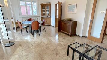 Un coin repas avec une table ronde, des chaises, un buffet et une table en verre au premier plan.