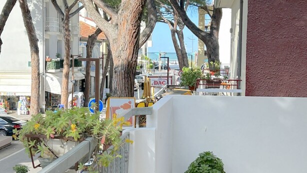 A street view with a white building, trees, and parked cars. - Prioli First Floor Flexrent Abyssinia (Riccione)